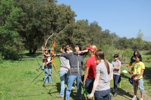 Olympian Khatuna Lorig (in red) runs coaching clinics all over the country for young archers in the Junior Olympic Archery Development (JOAD) program. Photo courtesy of Pasadena Roving Archers.