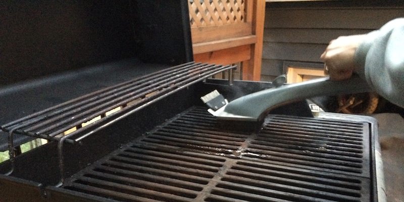 brush using steam to clean grate on grill