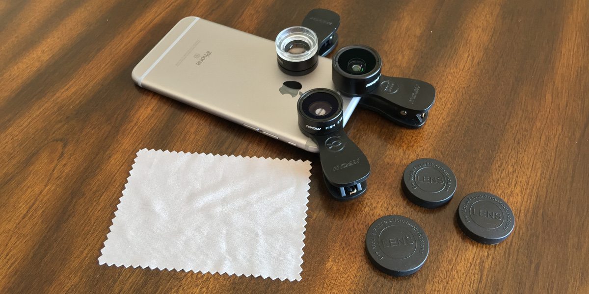 An iPhone with the three clip-on lenses attached, also showing the lens caps and cleaning cloth.