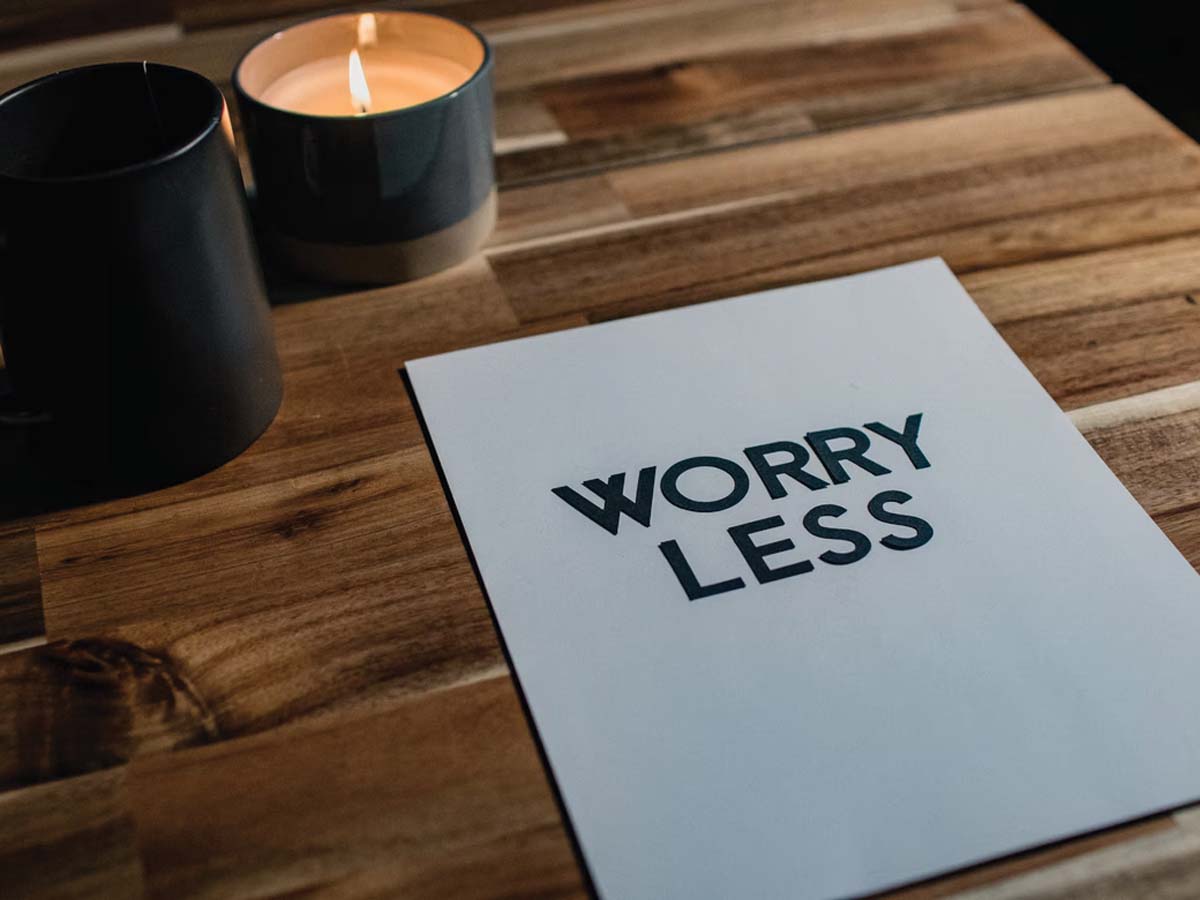 Candle next to sign saying "Worry Less"
